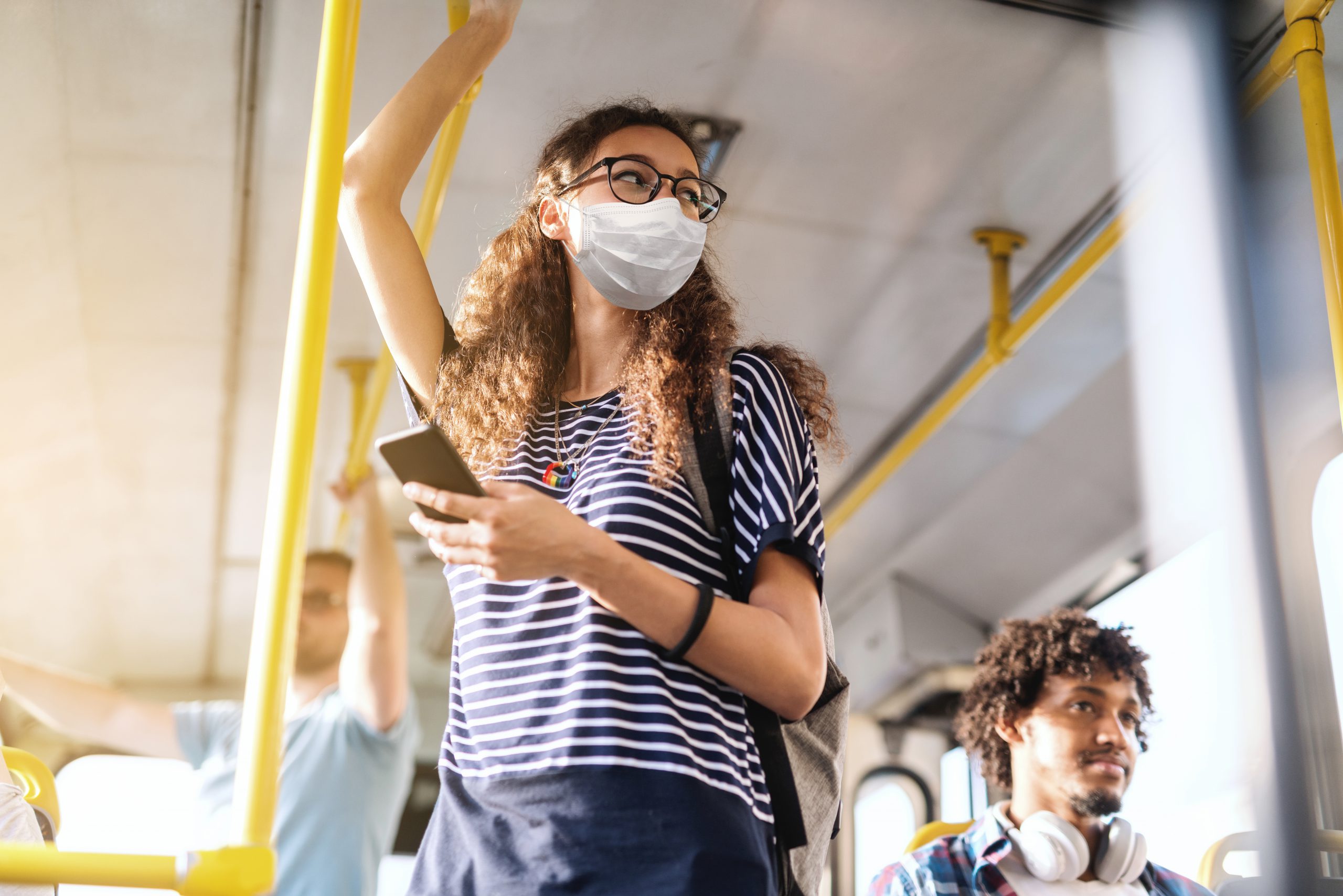 Woman standing on light rail wearing a face mask